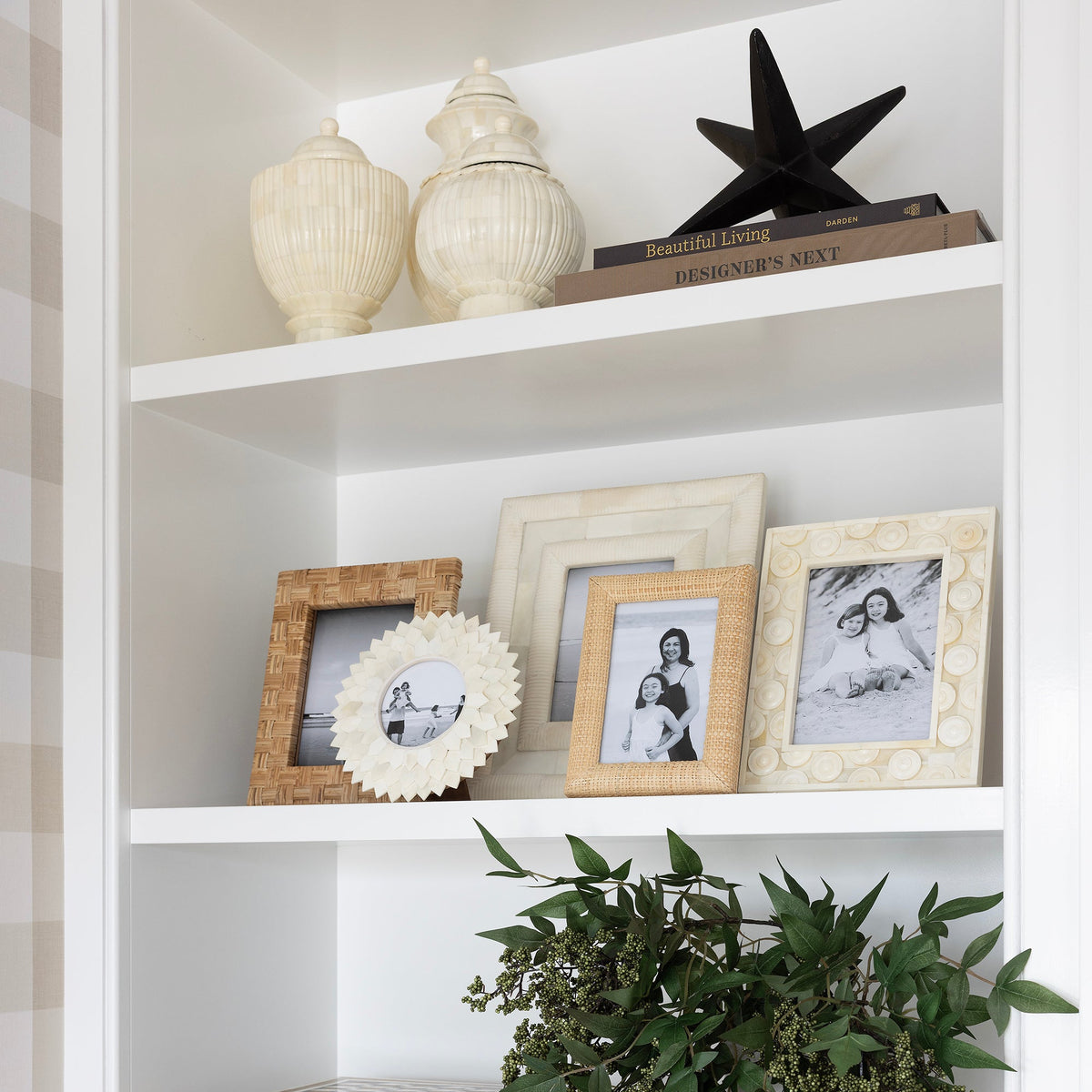 Decorative bookshelf with various items including framed photos, a horse statue, and plants.