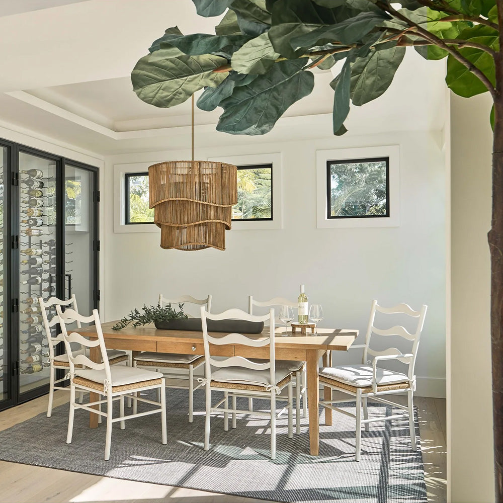 Image of white wave chairs around a dining table. Styled with a large faux fiddle leaf fig tree in the front corner, and a large feature woven pendant light in the centre of the table.