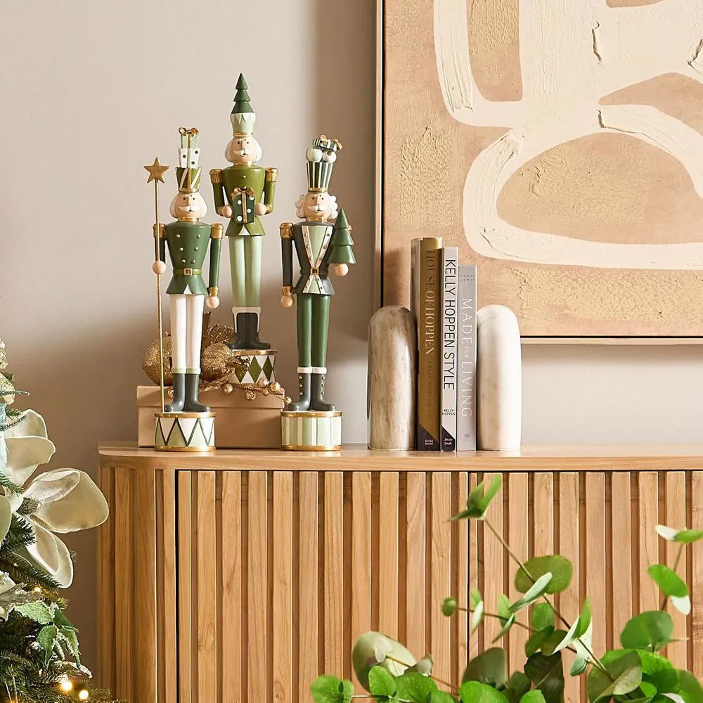 Decorative nutcrackers on a wooden cabinet with books and a plant.