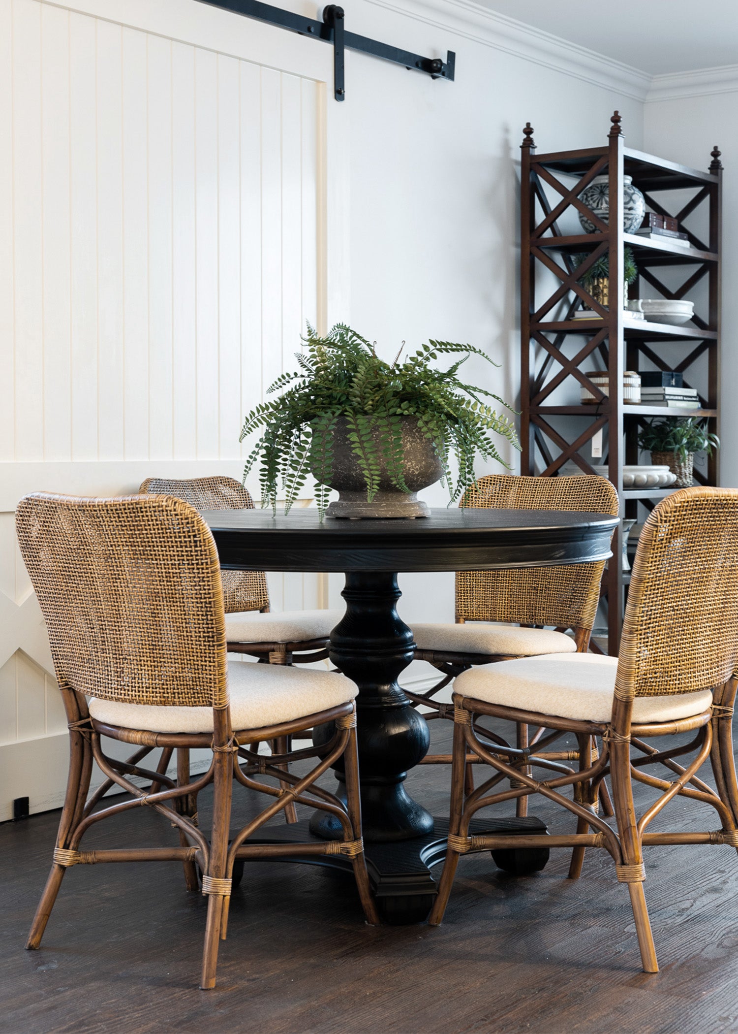 Palm woven dining chairs featured with our black brynmore round table. An arrangement of faux ferns is placed in the centre of the table. 