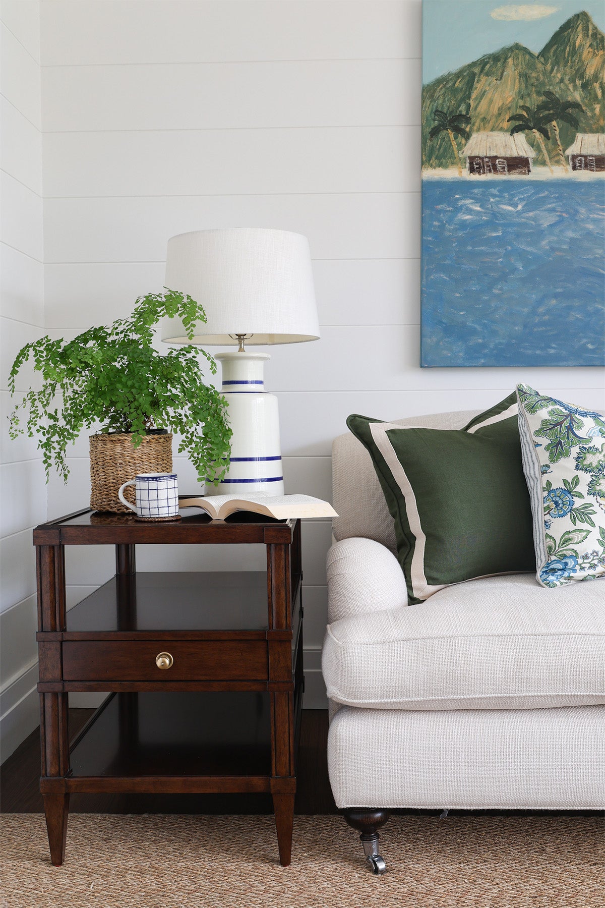 Living room with a side table, lamp, and sofa with decorative pillows.